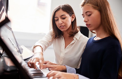 piano teacher and student 
            sitting at a piano
